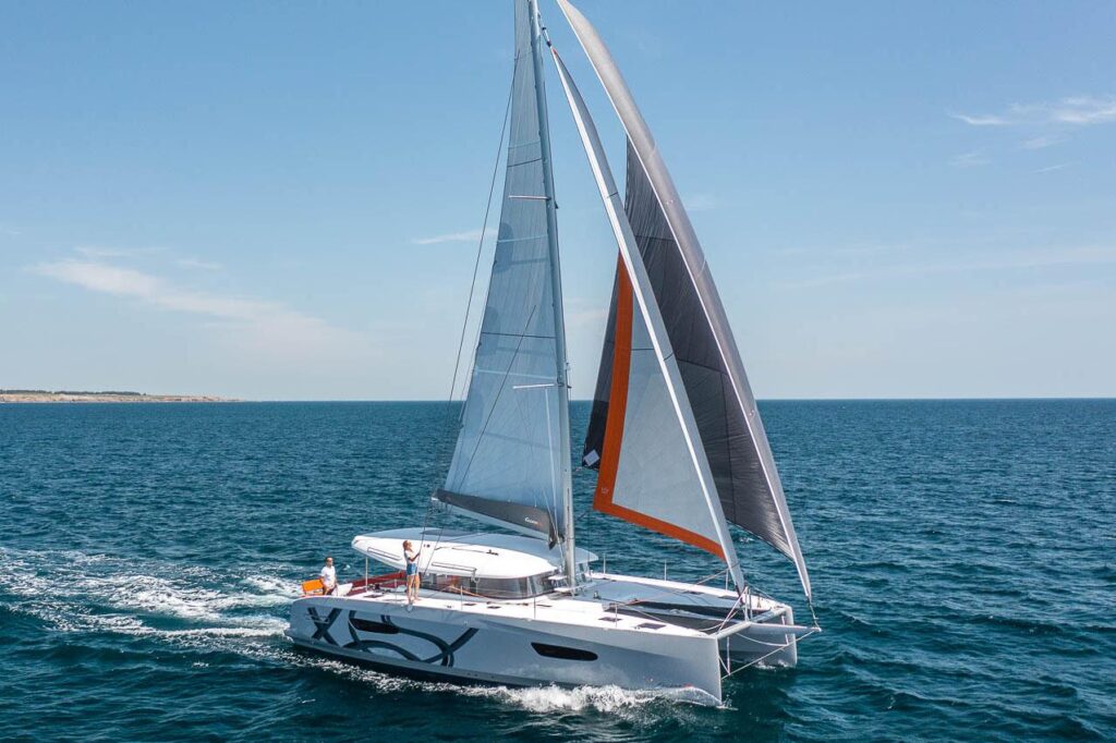 Manufacturer Provided Image: 2025 Excess 14 catamaran sailing on open sea under clear blue sky.